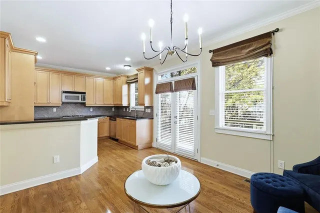 a kitchen with stainless steel appliances granite countertop a refrigerator a sink dishwasher a dining table and chairs with wooden floor