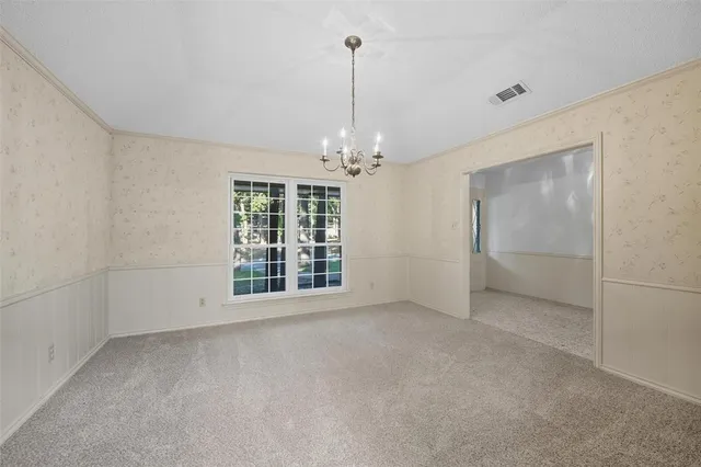 an empty room with chandelier fan and refrigerator