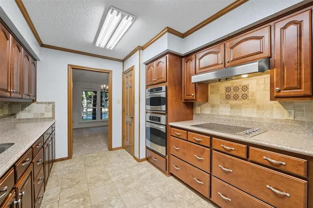 a large kitchen with stainless steel appliances granite countertop a stove refrigerator and cabinets