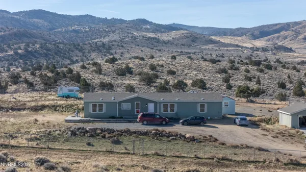 a front view of a house with a yard and mountain