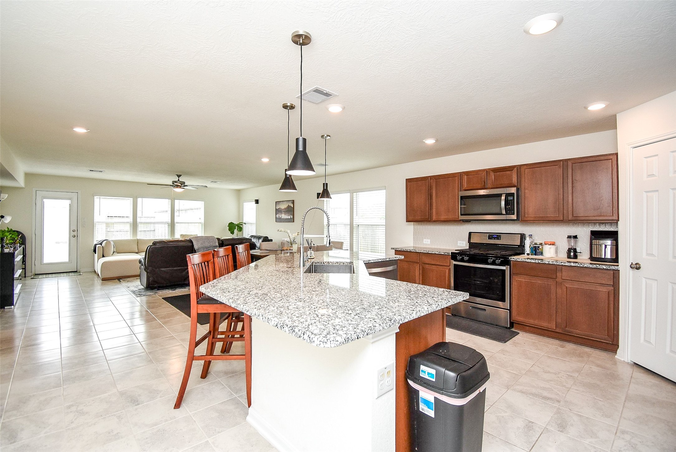 5912 Whitewing Road Rosenberg, TX 77469 - Photo 13 of 25 a kitchen with stainless steel appliances kitchen island granite countertop a sink a stove and a wooden cabinets