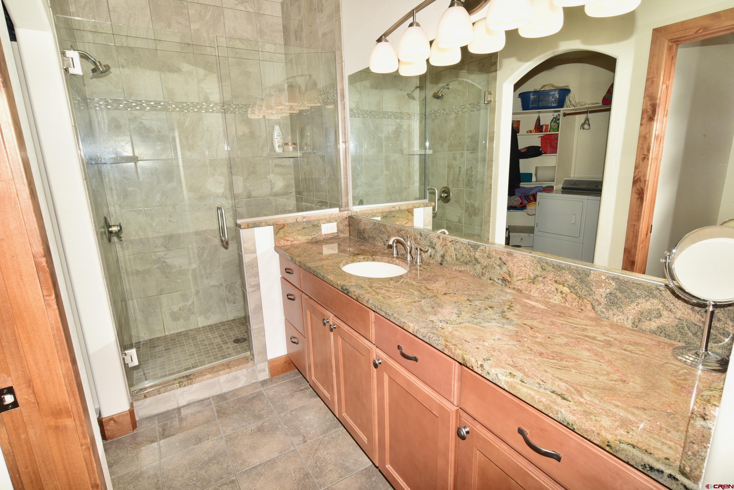 2136 Signature Ridge Lane Montrose, CO 81401 - Photo 26 of 32 a bathroom with a granite countertop sink a mirror and a shower