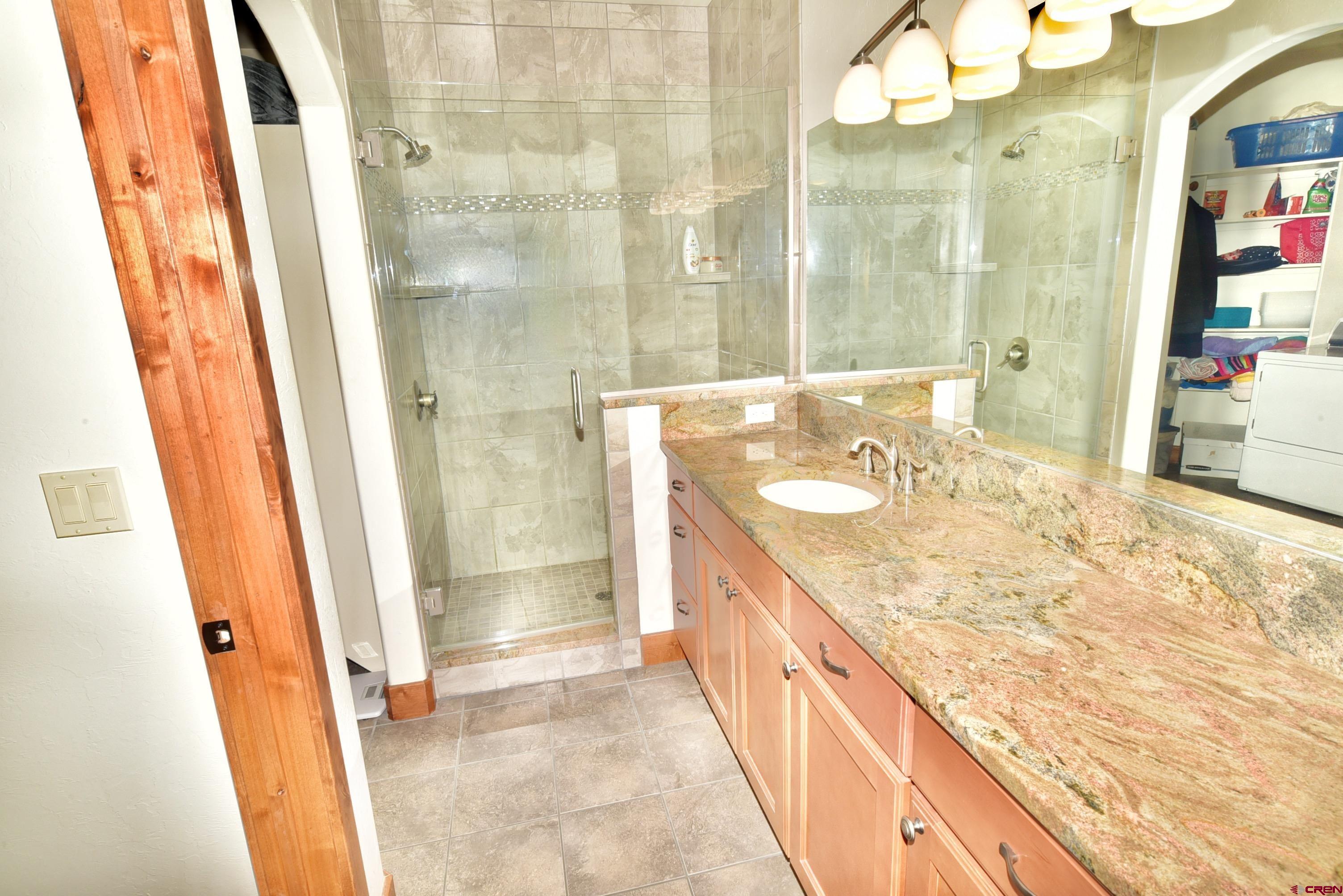2136 Signature Ridge Lane Montrose, CO 81401 - Photo 27 of 32 a bathroom with a granite countertop sink a mirror and shower