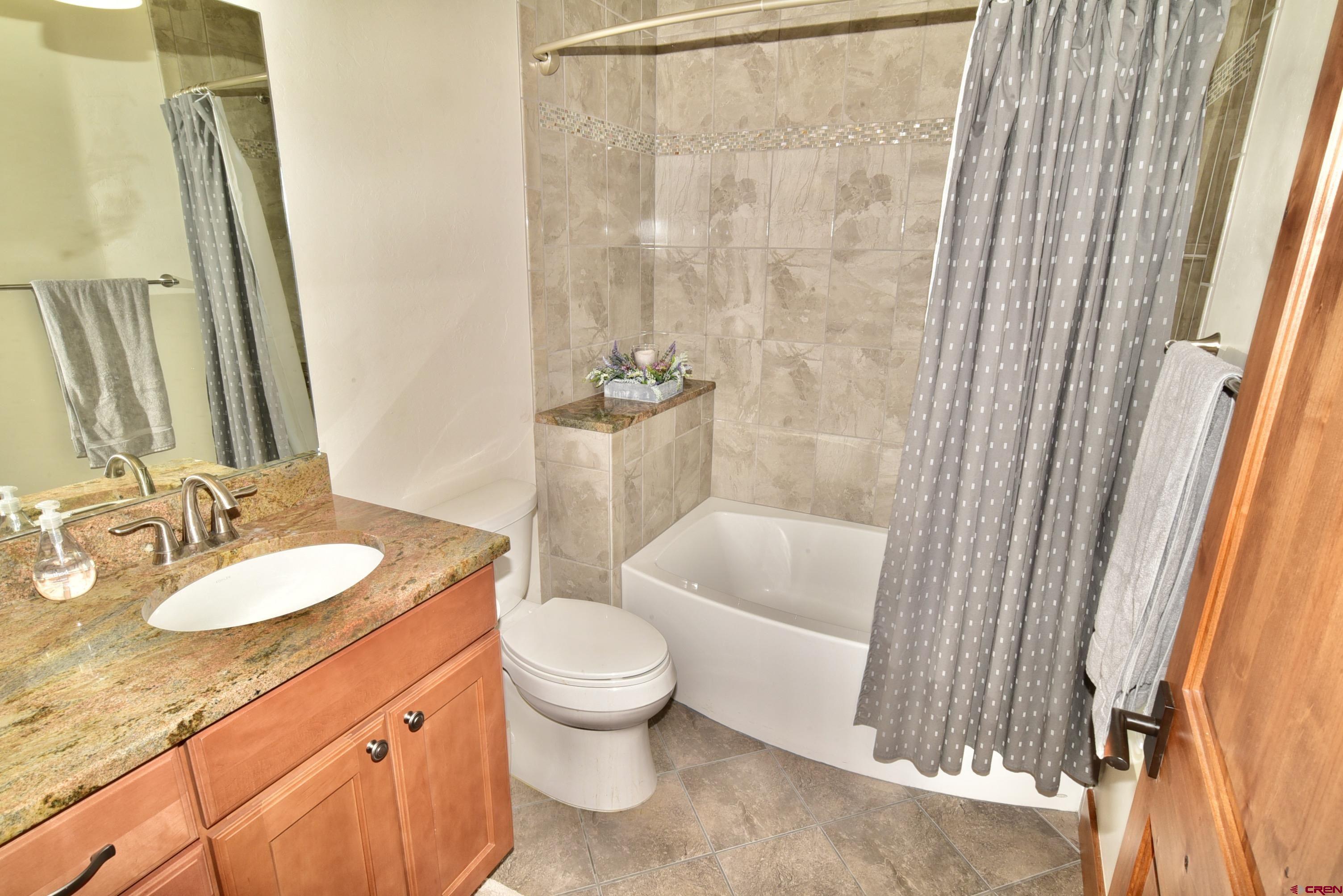 2136 Signature Ridge Lane Montrose, CO 81401 - Photo 32 of 32 a bathroom with a granite countertop sink toilet a mirror and shower
