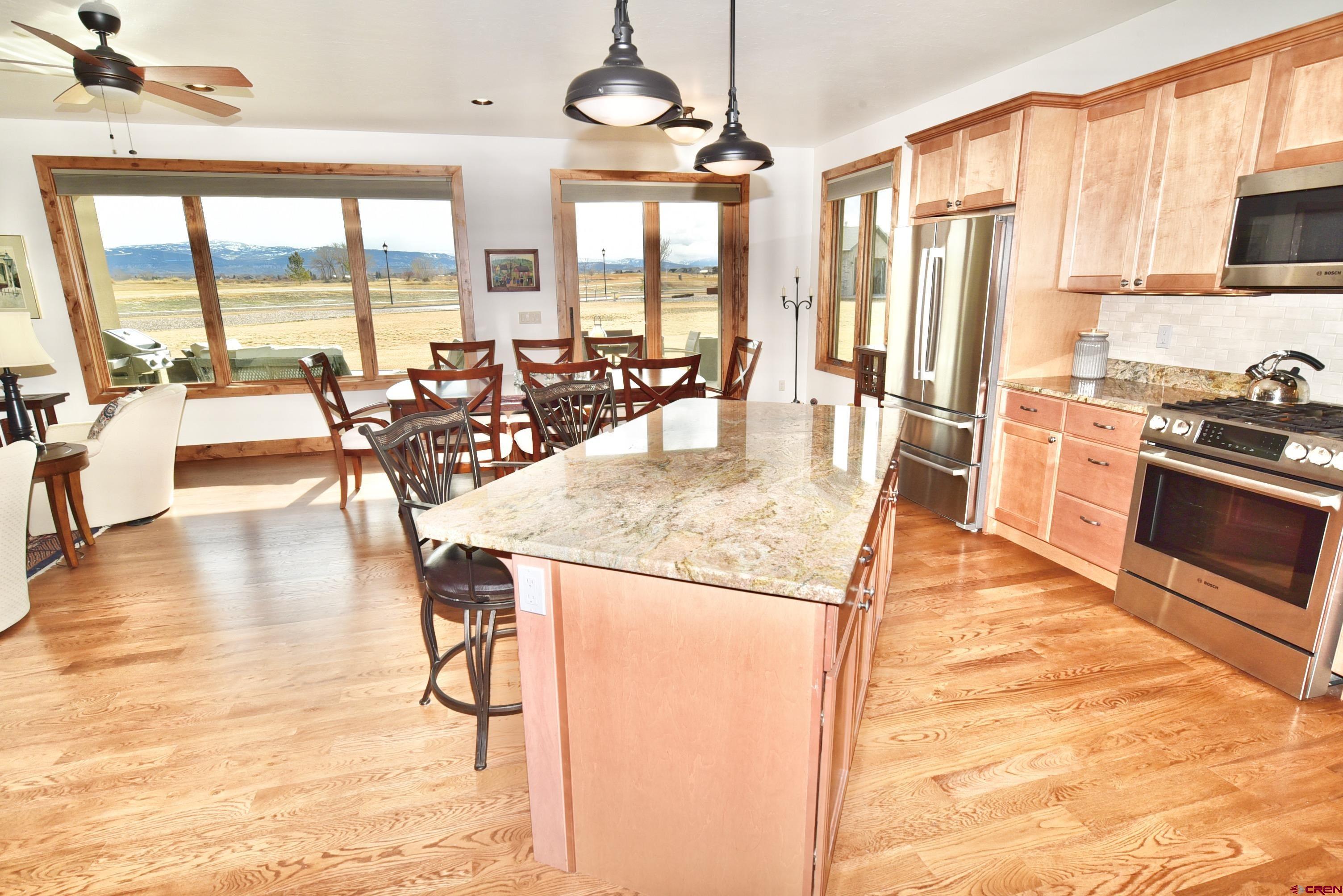 2136 Signature Ridge Lane Montrose, CO 81401 - Photo 7 of 32 a kitchen with stainless steel appliances granite countertop a stove a refrigerator a stove and white cabinets with wooden floor