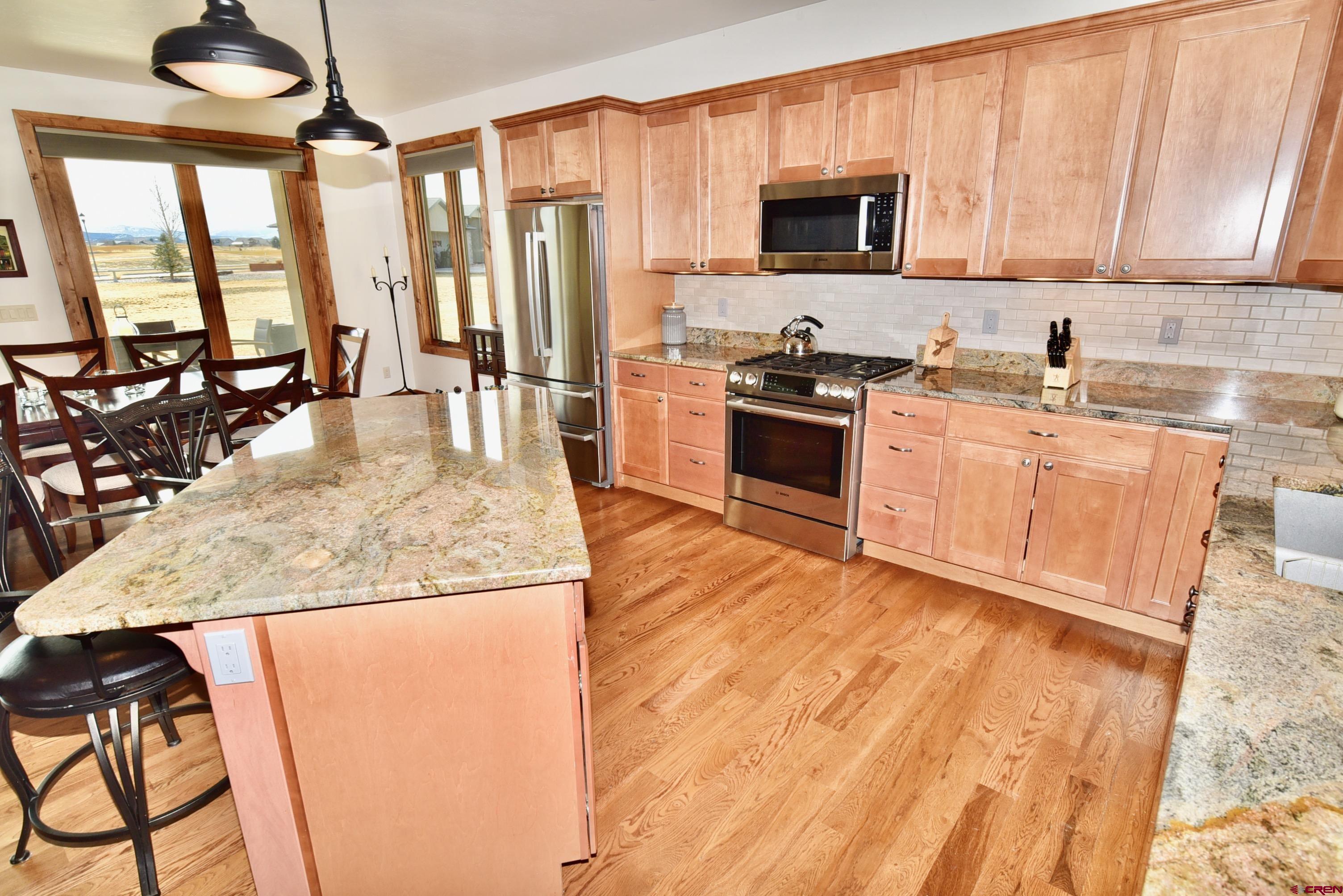 2136 Signature Ridge Lane Montrose, CO 81401 - Photo 8 of 32 a kitchen with stainless steel appliances granite countertop a stove a sink and a microwave