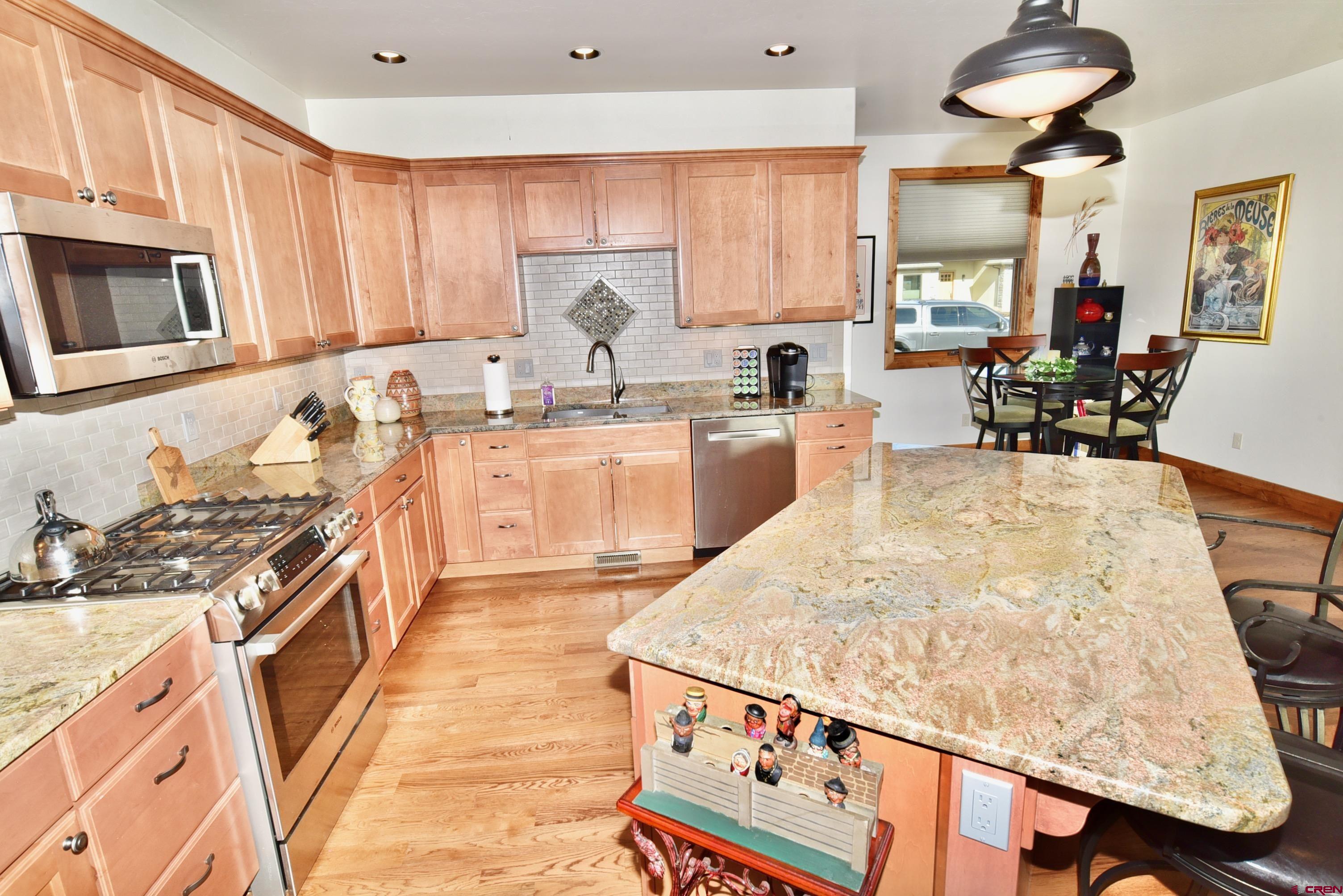 2136 Signature Ridge Lane Montrose, CO 81401 - Photo 10 of 32 a kitchen with stainless steel appliances granite countertop a stove top oven a sink dishwasher and cabinets with wooden floor
