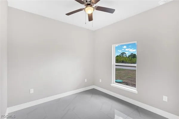 an empty room with a window and a ceiling fan