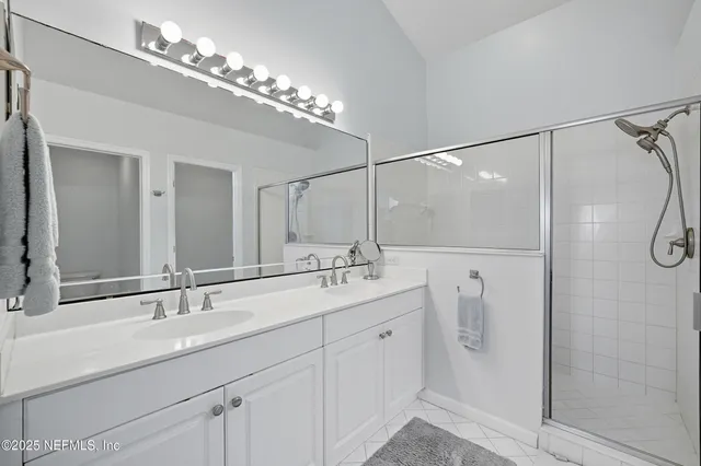 a bathroom with a double vanity sink a large mirror and shower