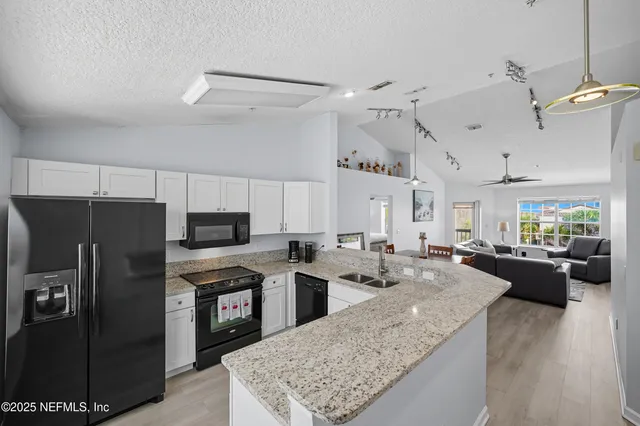 a large kitchen with kitchen island a refrigerator a stove a sink dishwasher a dining table and chairs with wooden floor