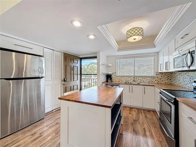 a kitchen with stainless steel appliances granite countertop hardwood floor sink stove and wooden cabinets
