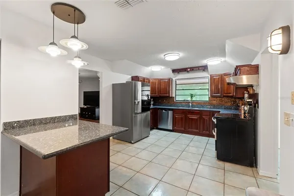 a kitchen with kitchen island granite countertop a stove cabinets and microwave