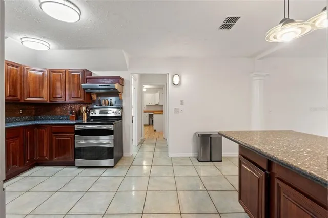 a view of a kitchen with stainless steel appliances granite countertop a refrigerator and a stove