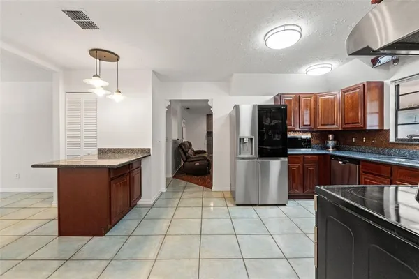 a view of a kitchen with stainless steel appliances granite countertop a refrigerator and a stove