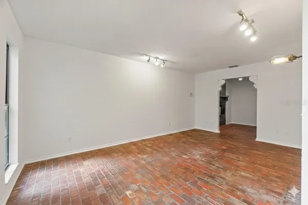 a view of an empty room with wooden floor and a ceiling fan