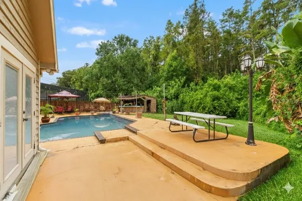 a view of a swimming pool with a patio and a yard