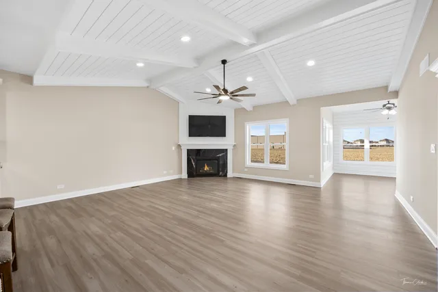 an empty room with wooden floor fireplace and windows