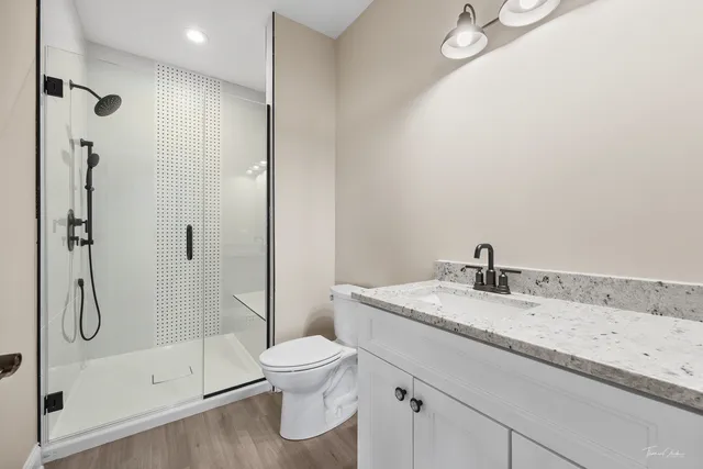 a bathroom with a granite countertop sink a toilet and shower