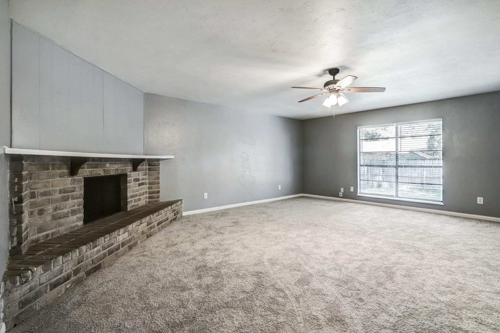 14107 Pinewest Drive Houston, TX 77049 - Photo 2 of 10 an empty room with windows and fireplace