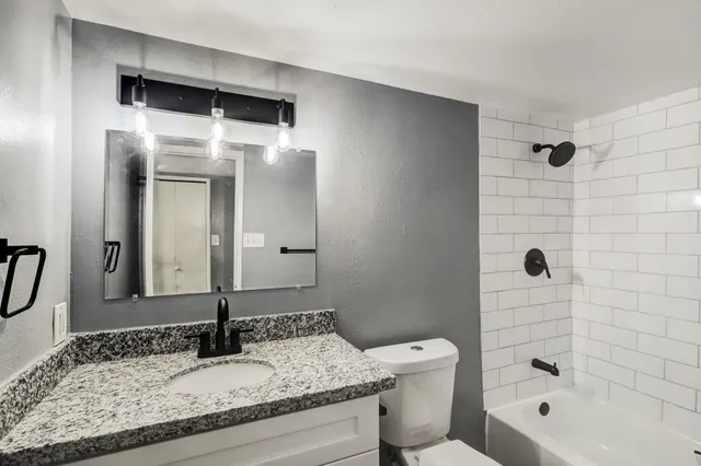 a bathroom with a granite countertop sink toilet and shower