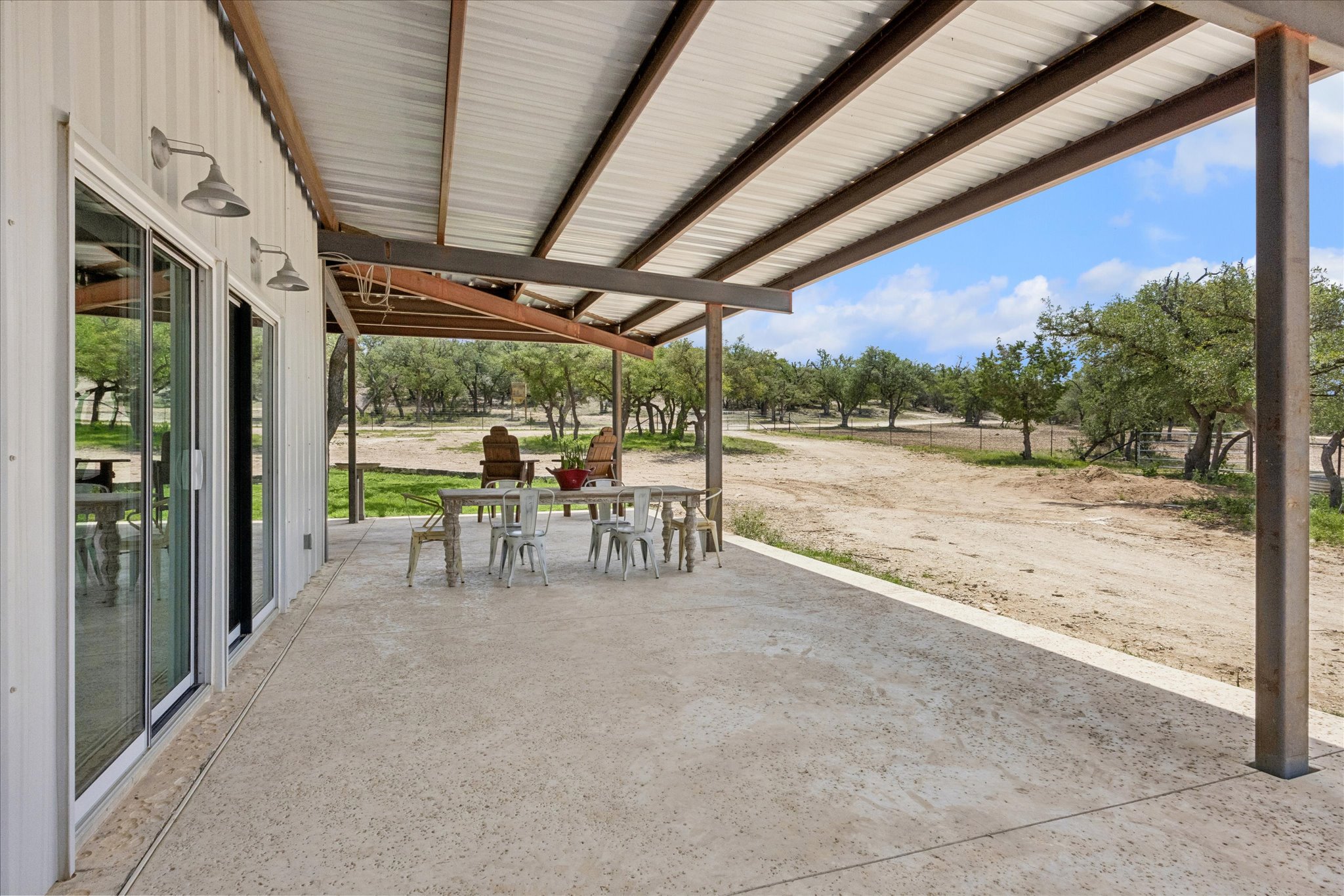 6411 West Fitzhugh Road Dripping Springs, TX 78620 - Photo 21 of 34 Expansive covered patio with a corrugated metal roof and exposed steel beams