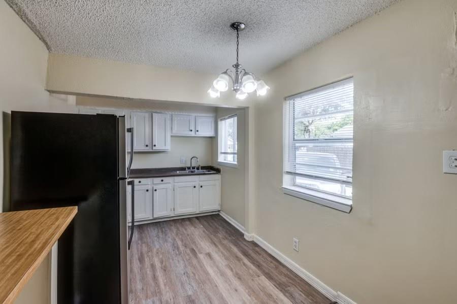 512 South Delaware Street, Unit 1 Irving, TX 75060 - Photo 3 of 9 a kitchen with granite countertop a refrigerator a sink dishwasher a stove and white cabinets with wooden floor