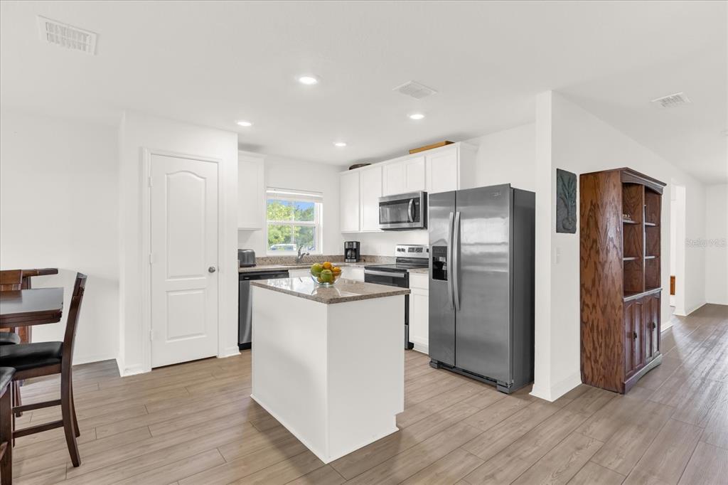 2134 Rio Grande Canyon Loop Poinciana, FL 34759 - Photo 5 of 22 a kitchen with a refrigerator a microwave oven a sink with wooden floor and cabinets