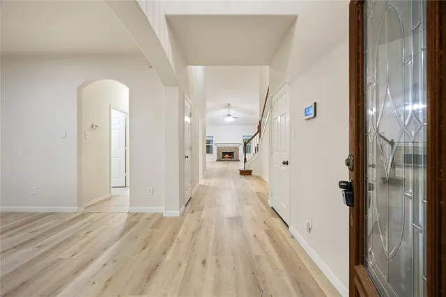 a view of a hallway with wooden floor and a bathroom