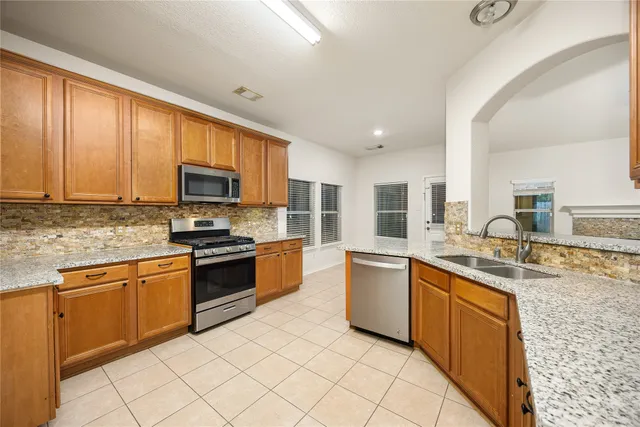 a large kitchen with stainless steel appliances granite countertop a stove top oven a sink dishwasher a dining table and chairs with wooden floor