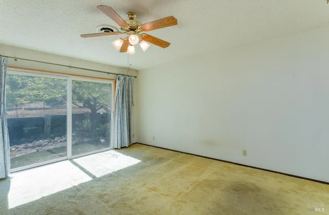 a view of a room with a ceiling fan and window