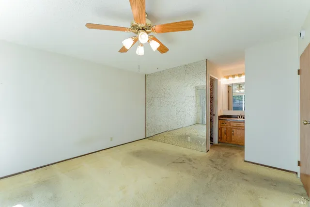 an empty room with a chandelier fan and a large window