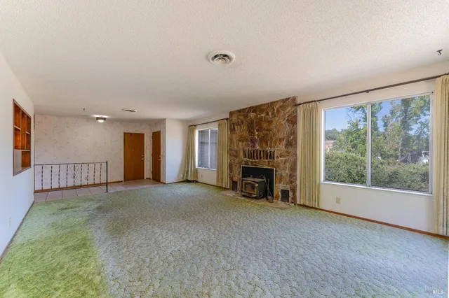 a view of an empty room with a fireplace and a window