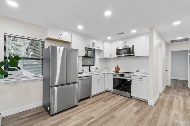 a kitchen with a sink white cabinets and stainless steel appliances