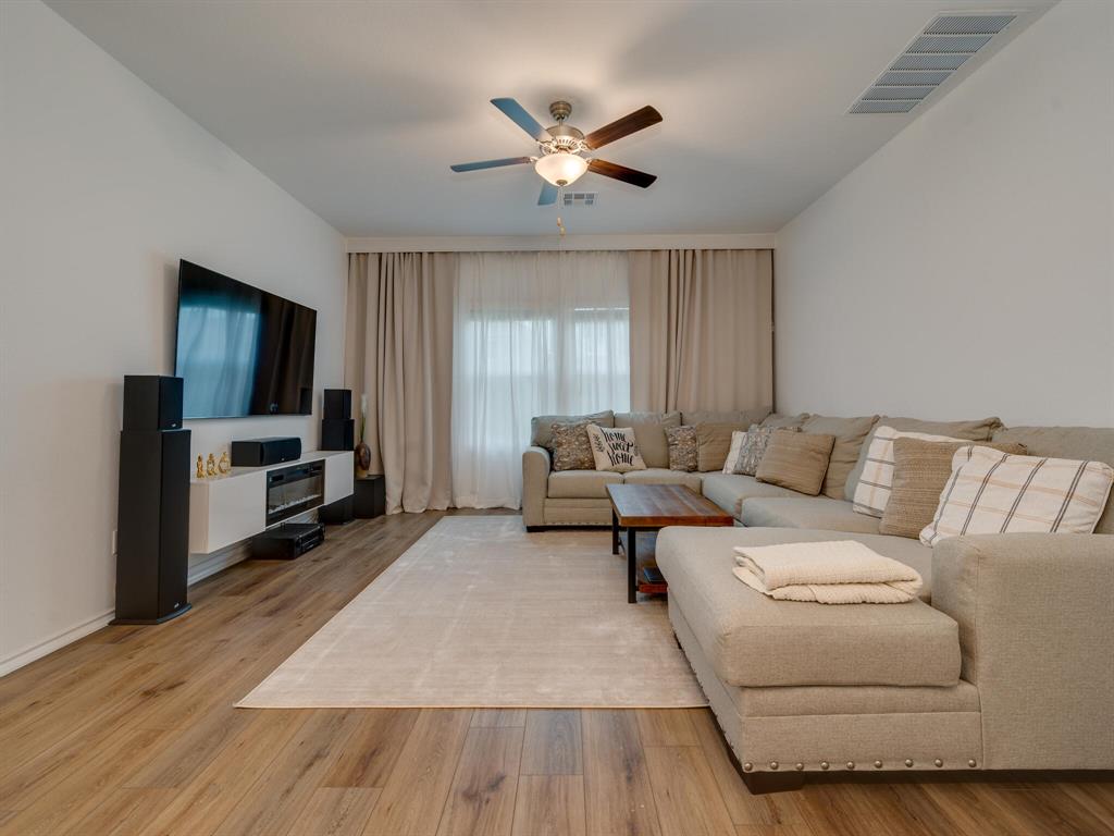 1208 Sweetspire Street Leander, TX 78641 - Photo 11 of 36 Spacious living area featuring wood-finish flooring, a ceiling fan with integrated lighting, and a window with light-filtering curtains