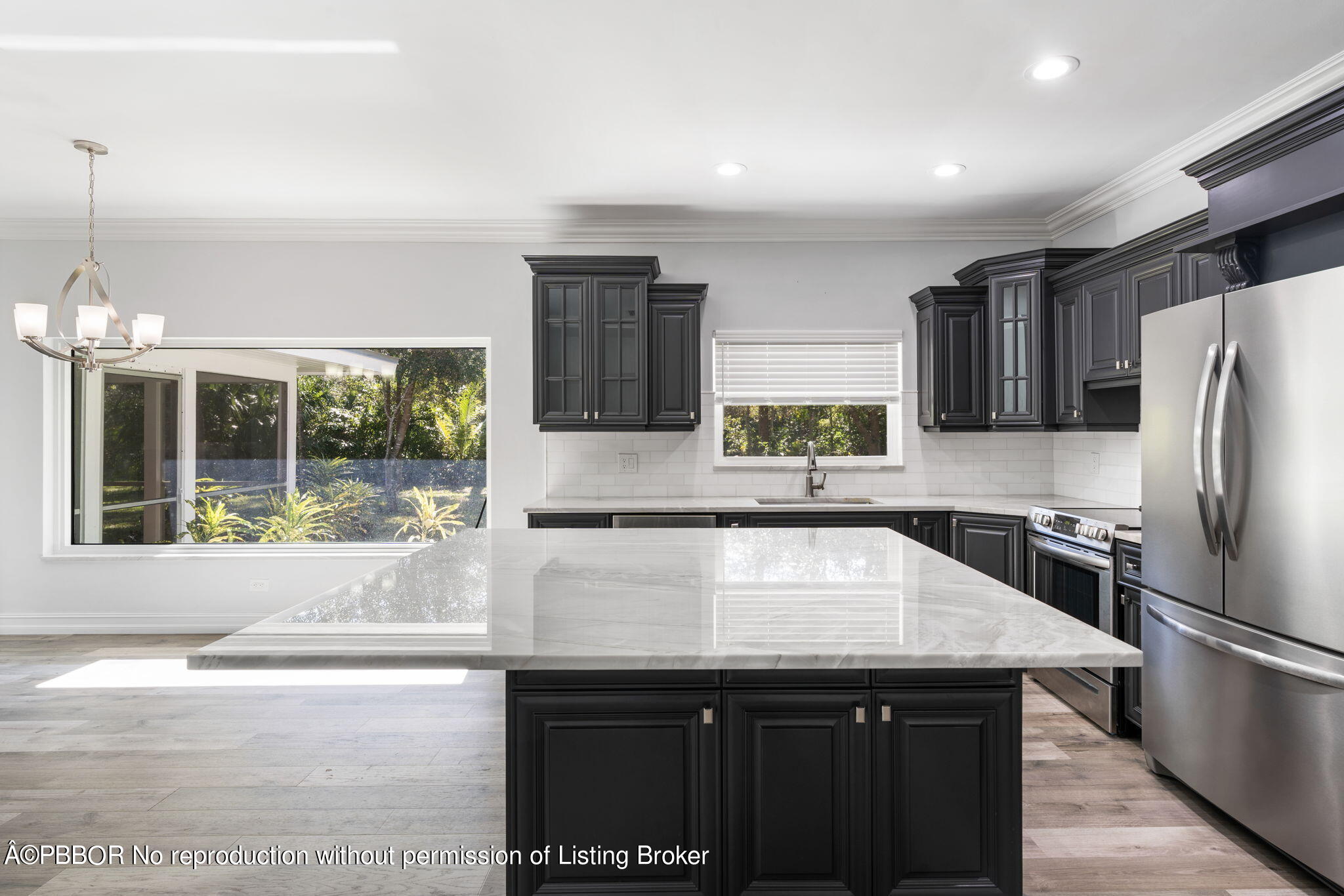 5608 Old Fort Jupiter Road Jupiter, FL 33458 - Photo 14 of 59 a kitchen with a sink a kitchen island and stainless steel appliances wooden cabinets