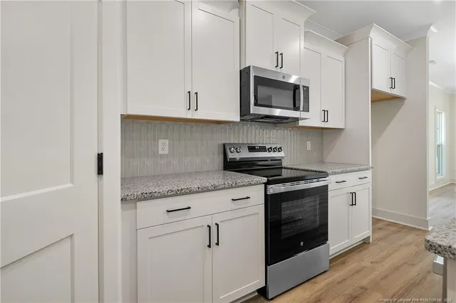 a kitchen with stainless steel appliances granite countertop white cabinets and a stove top oven