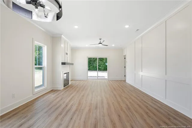 an empty room with wooden floor cabinet and windows