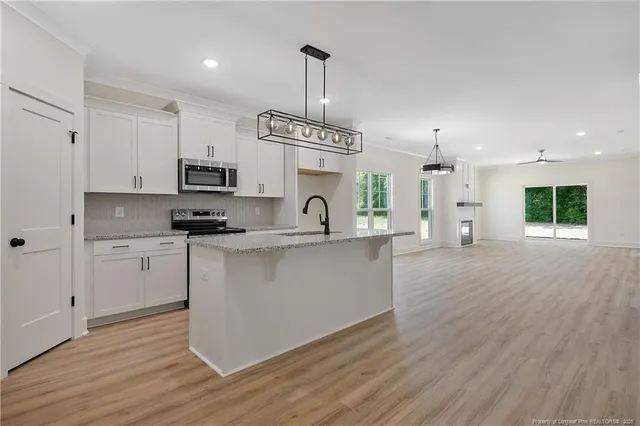 a kitchen with stainless steel appliances kitchen island a white cabinets and a wooden floor