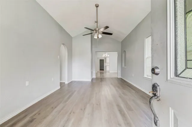 a view of a livingroom with a fireplace a ceiling fan and windows