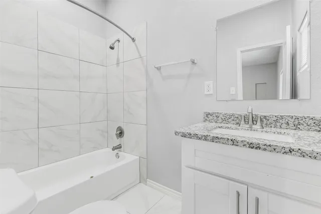 a bathroom with a granite countertop sink a mirror and a bathtub