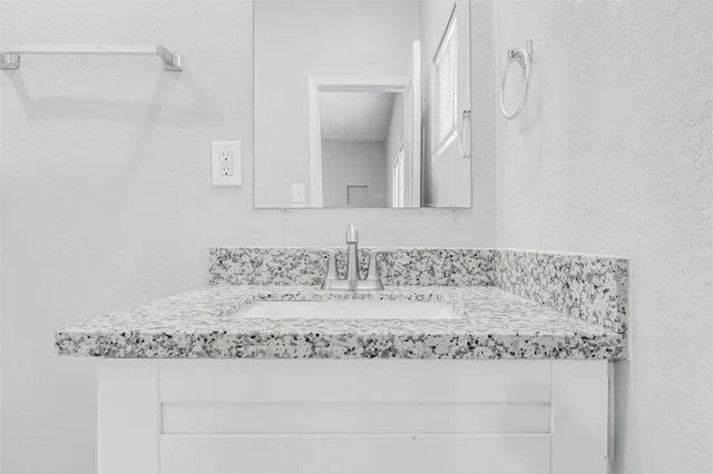 a bathroom with a granite countertop sink and a mirror