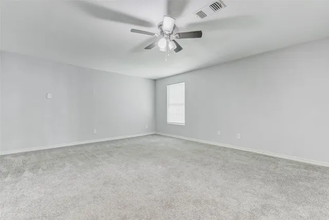 an empty room with a chandelier fan and windows