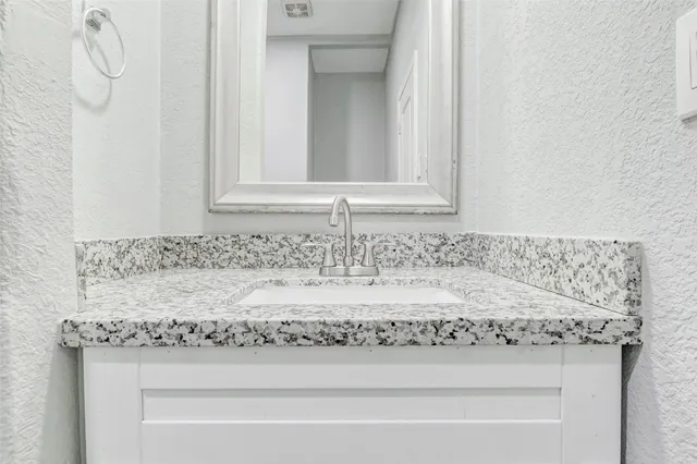 a bathroom with a granite countertop sink and mirror