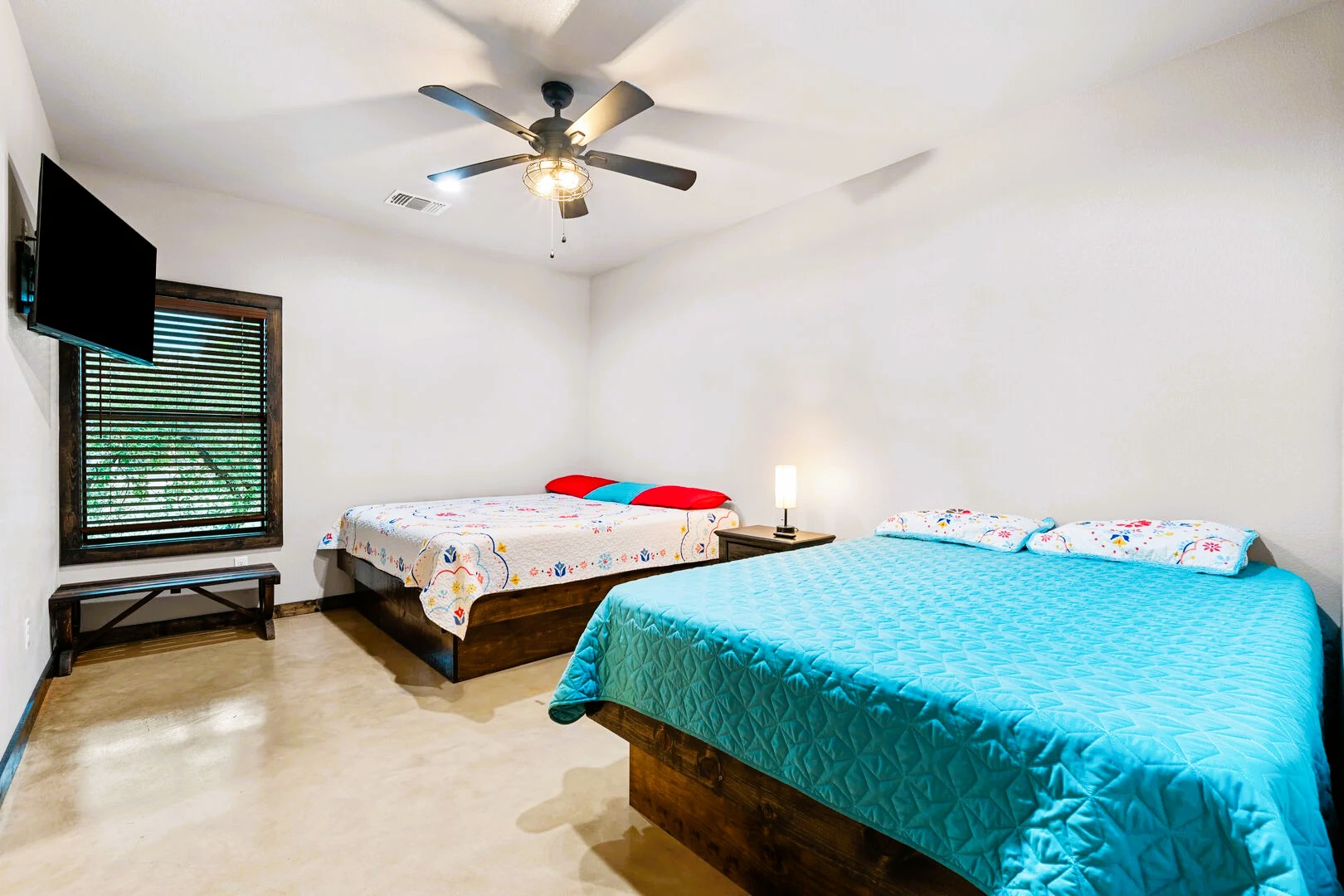 1718 Mountain Valley Road Concan, TX 78838 - Photo 17 of 40 Smooth concrete floors and a stained wood window frame define this inviting bedroom space.
