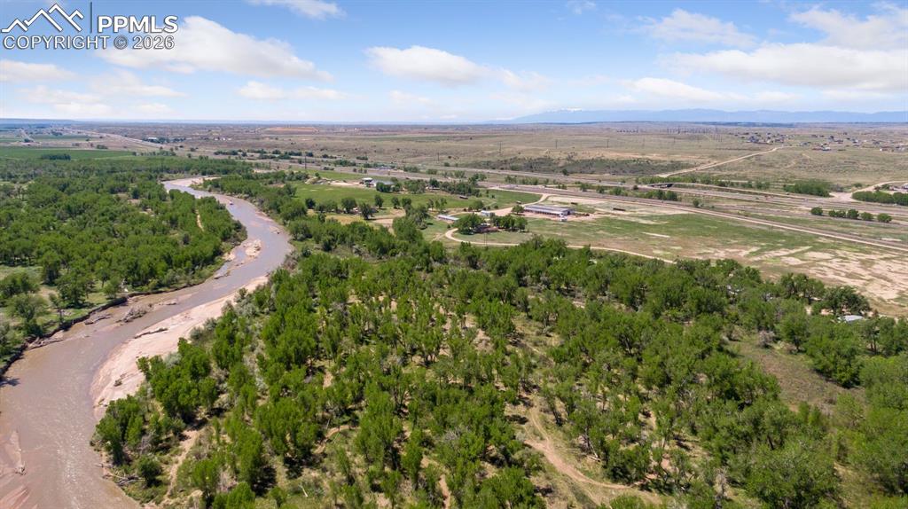 Aerial view of 165-acre property along Fountain Creek with expansive open land, natural creek corridors, and sweeping views toward Pikes Peak, located directly across from Pikes Peak International Raceway.
