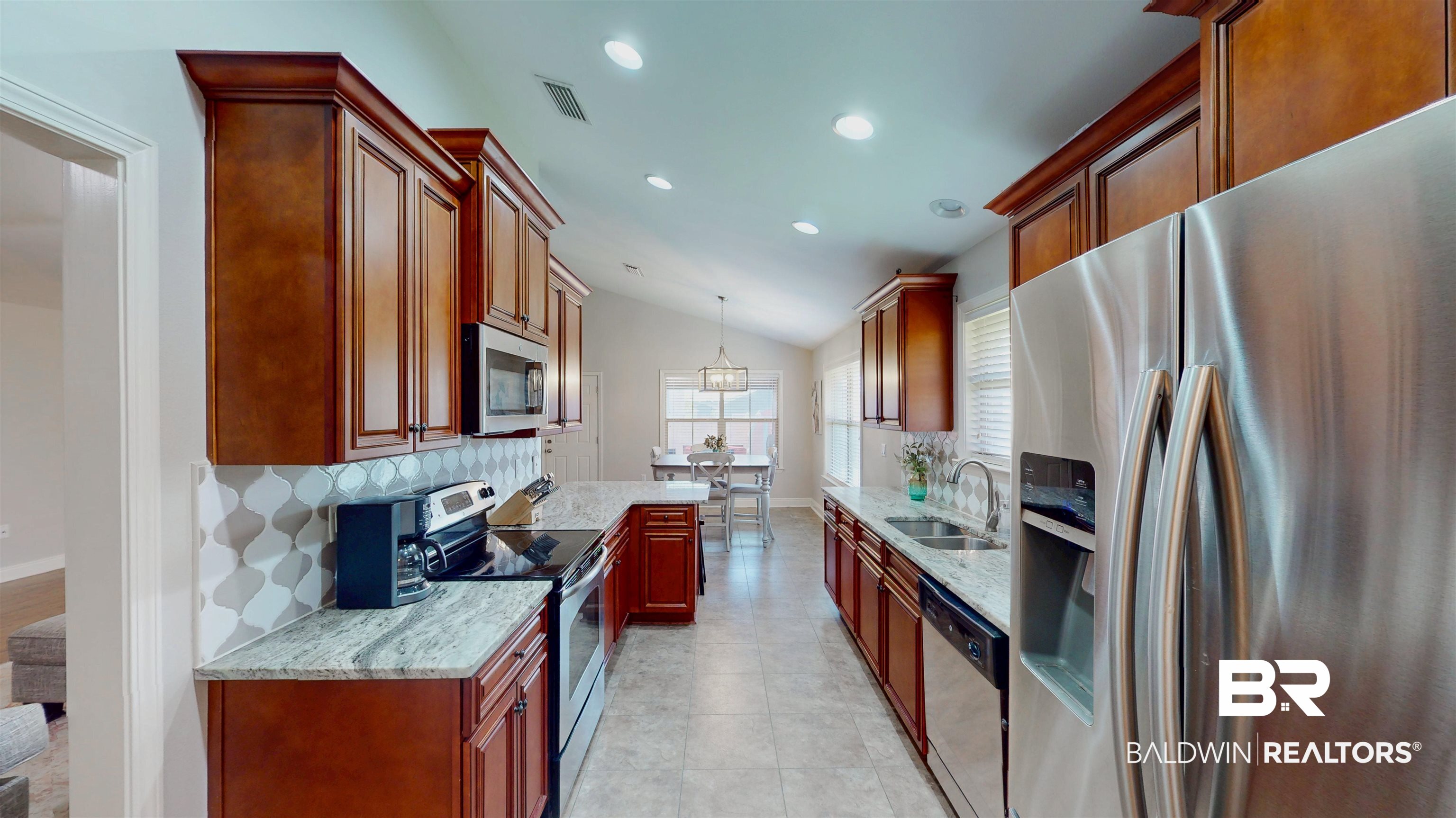 1704 Arcadia Drive Foley, AL 36535 - Photo 12 of 52 Kitchen with appliances with stainless steel finishes, decorative backsplash, vaulted ceiling, light stone countertops, and recessed lighting