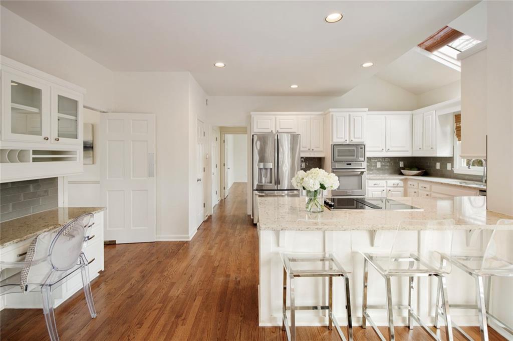 715 Winterwind Way Roswell, GA 30075 - Photo 17 of 83 a kitchen with kitchen island granite countertop a stove a sink a refrigerator and white cabinets with wooden floor