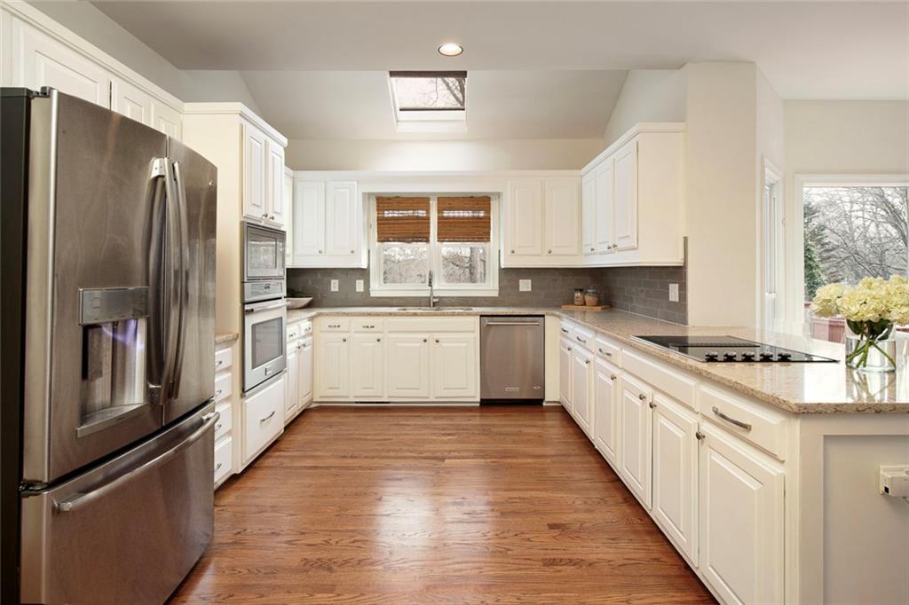 715 Winterwind Way Roswell, GA 30075 - Photo 20 of 83 a large kitchen with stainless steel appliances granite countertop a stove a sink dishwasher a refrigerator and white cabinets with wooden floor