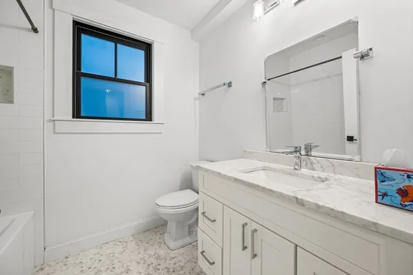 a bathroom with a granite countertop sink mirror vanity and toilet