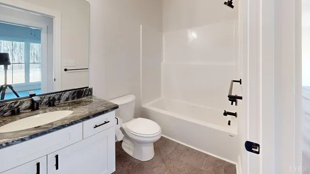 a bathroom with a granite countertop sink toilet mirror and bathtub